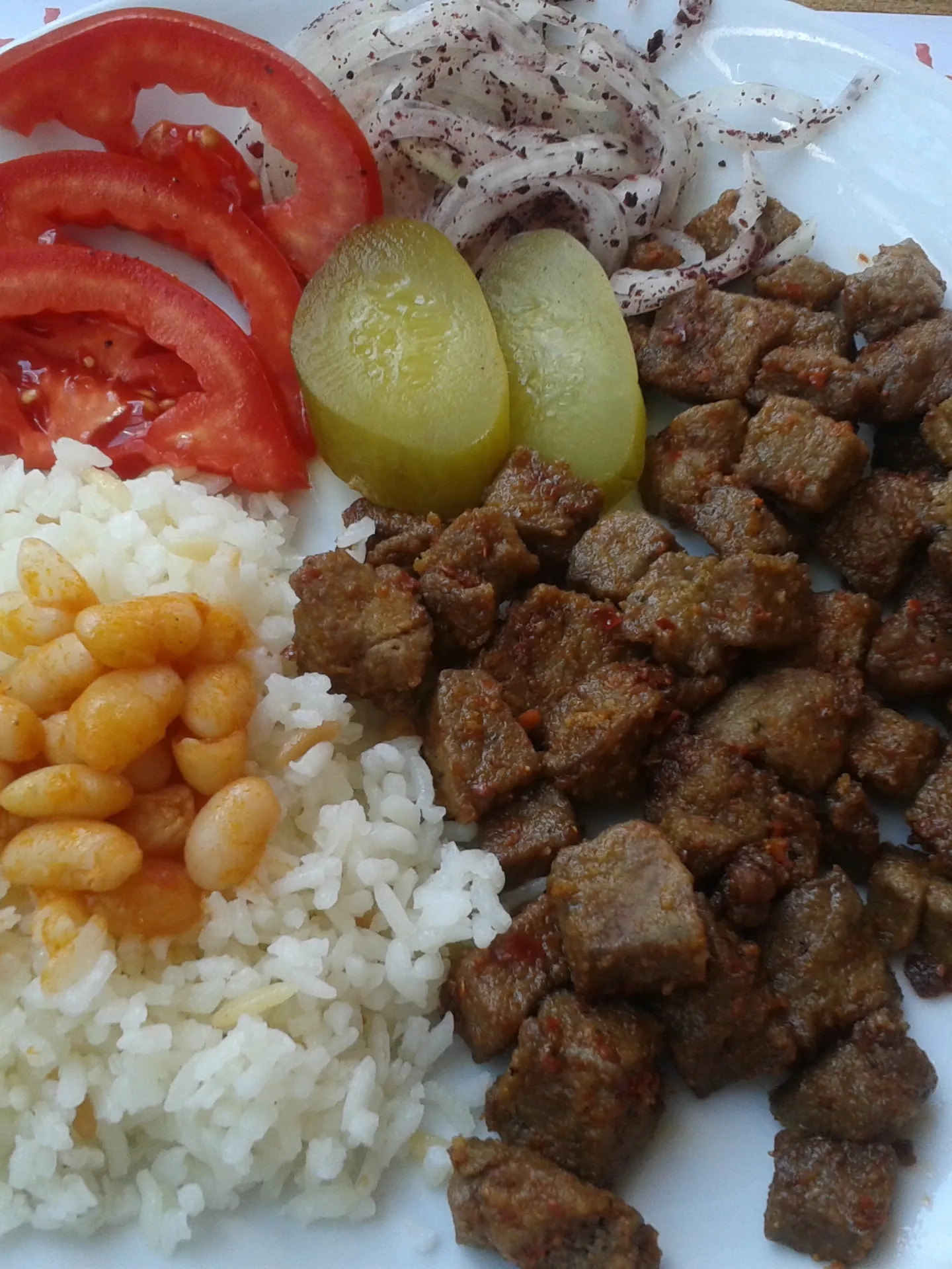Arnavut ciğeri: Arnavut ciğeri (made with lamb liver) with "pilav" (Turkish pilaf), "turshu", tomato slices, and chopped onions with sumak. The pilav has a bit of "kuru fasulye" on top