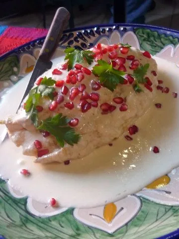Chiles en nogada: Chili stuffed with minced meat and fruits, served with nogada sauce and decorated with pomegranate