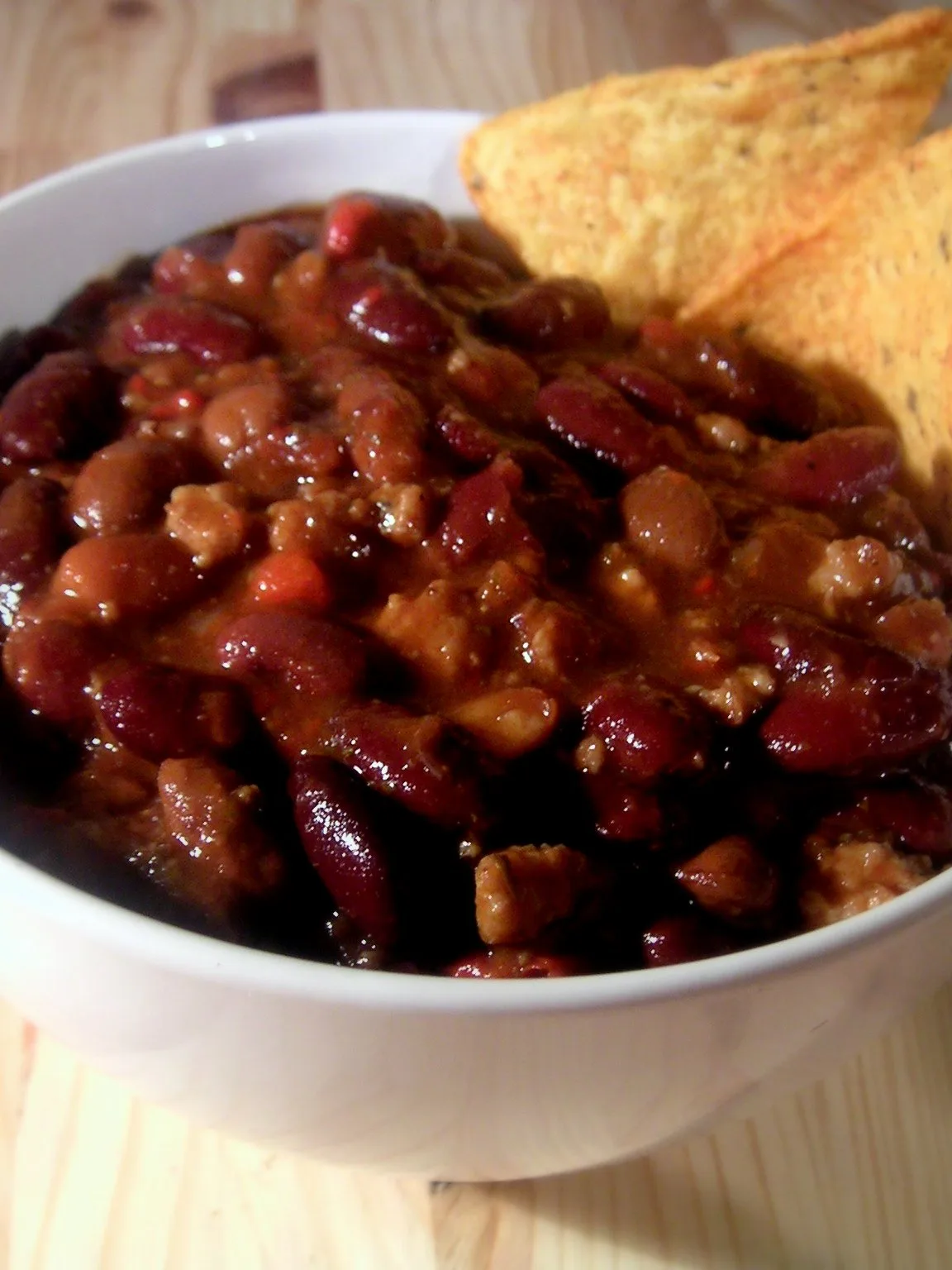 chili: Bowl of Chili con Carne, made of ground pork, cubed beef, beans, tomatoes and hot peppers. Decorated with two Tortilla chips