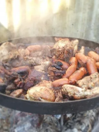 Discada: mixture of meats and seafood cooked in white wine and covered with sheets ready for cooking vegetables on a platter with coal iron