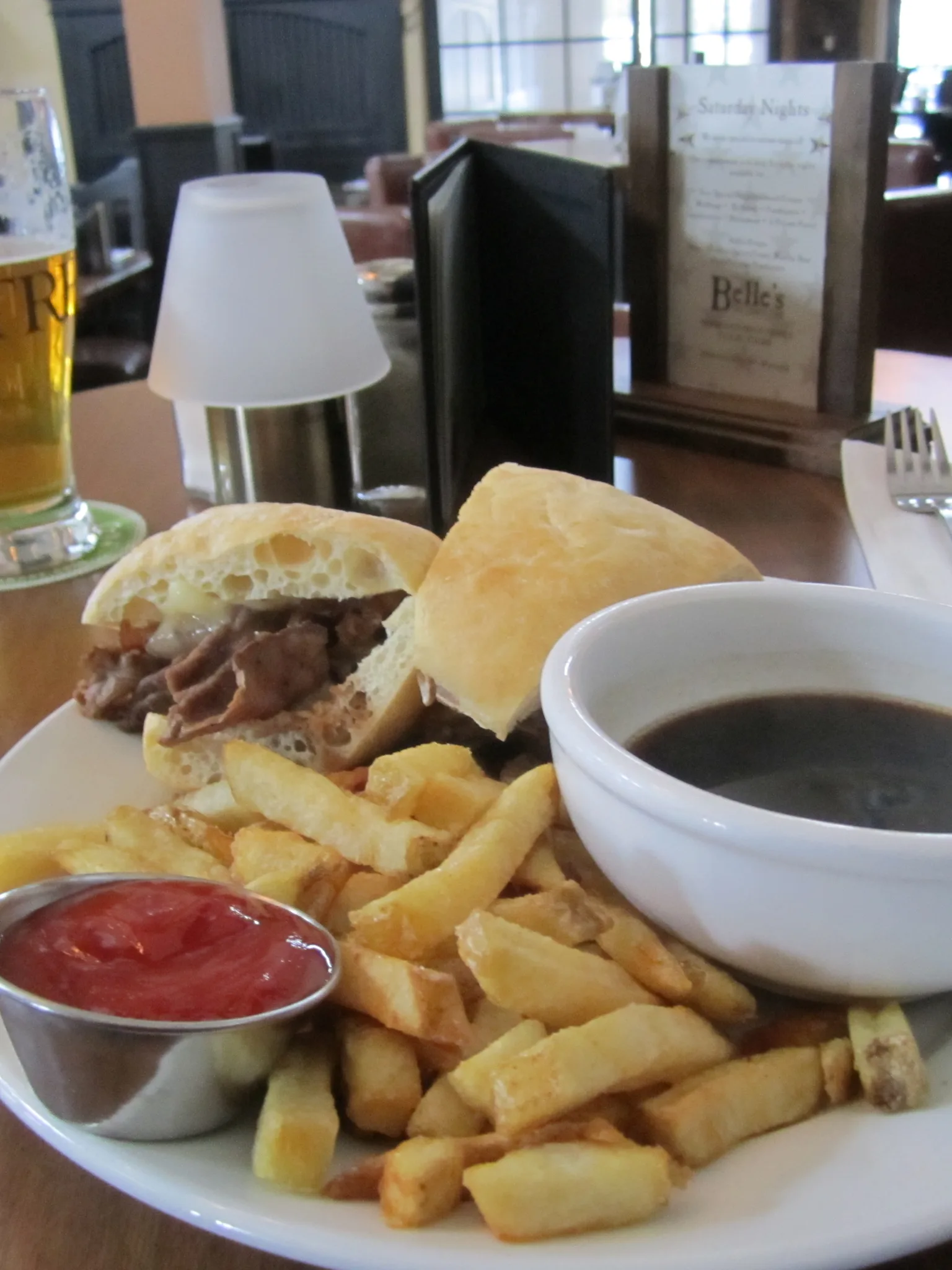 French dip sandwich: Roast beef dip, french fries, au jus, ketchup, beer and fire in background