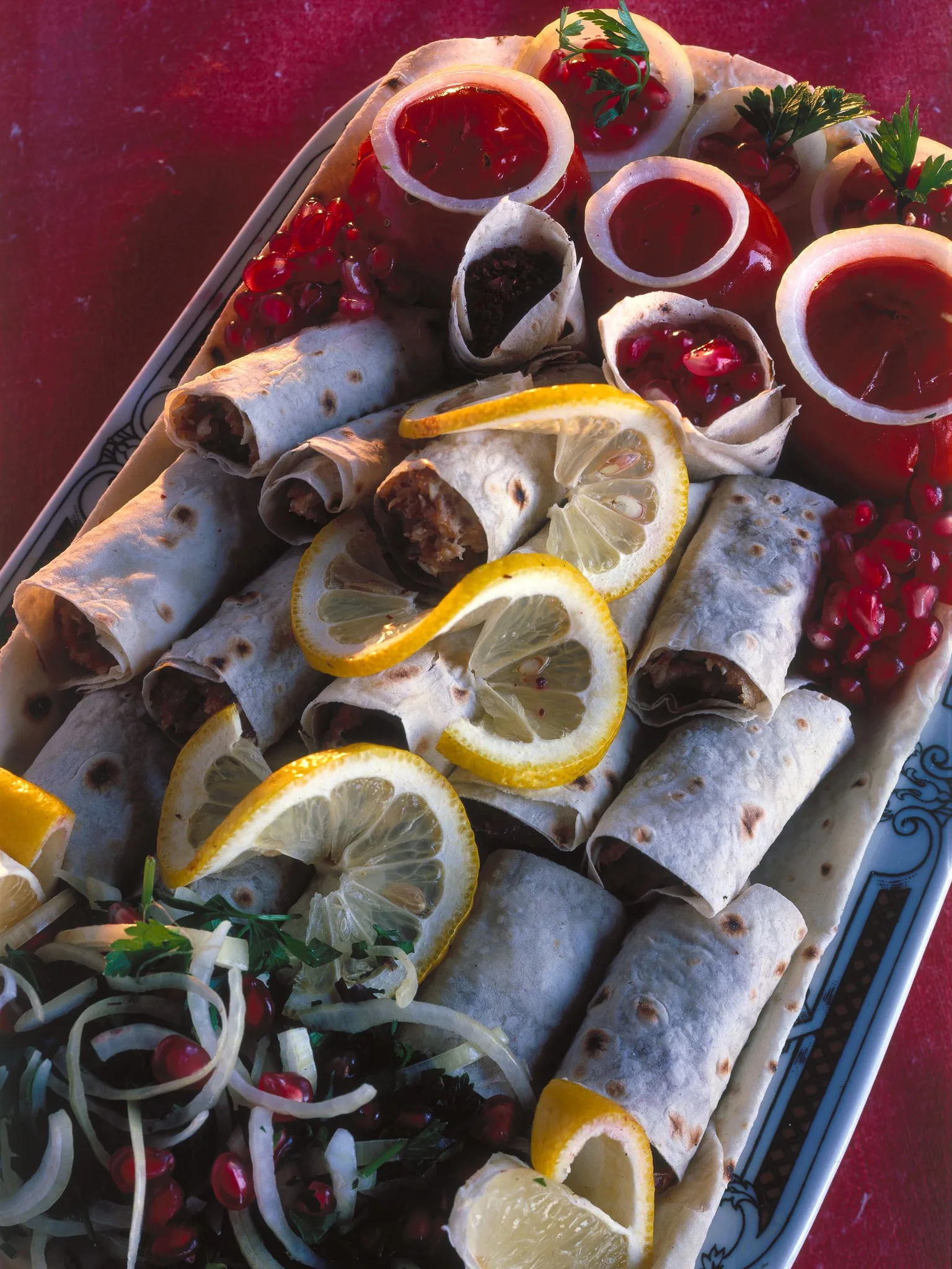 Lula kebab: Lyulya kebab served in lavash, and with fried tomatoes, pomegranate grains, onion and lemon pieces