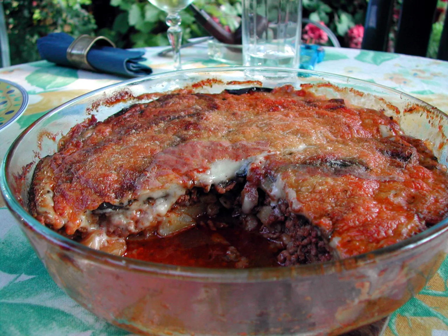 Greek moussaka in a baking dish, golden béchamel topping visible over layered aubergine