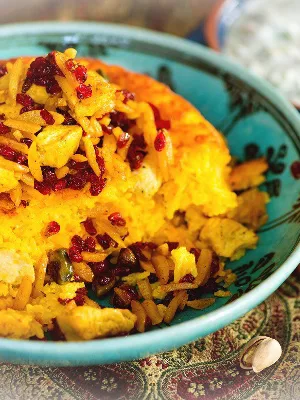 Tah Chin: Saffron infused crisp rice cake cooked with chicken and yoghurt. Finished with barberries and sprinkled with pistachios